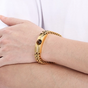 Détail d'un bracelet en titane doré avec pierre oeil de tigre et incrustations de zircon