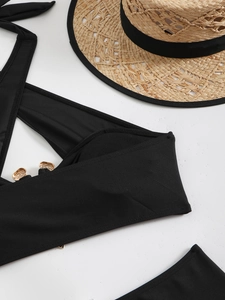 Detail of black bikini with gold snake-pattern buckle and elegant straw sun hat