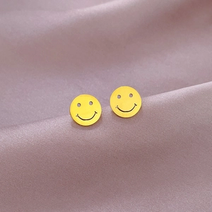 Macro shot of minimalist gold smiley face stud earrings on soft purple silk fabric