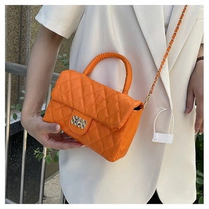 Close-up of orange quilted crossbody bag featuring a gold buckle and chain strap