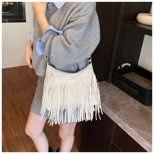Close-up of white leather shoulder bag featuring dense tassel fringe on a female model