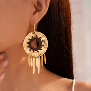 Gros plan de boucles d'oreilles bohèmes dorées avec pampilles feuilles sur un mannequin