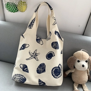 Detail of canvas tote bag featuring navy blue sea shell patterns on cream fabric
