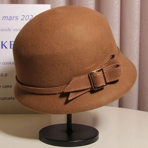 Détail d'un chapeau cloche en laine marron foncé avec nœud décoratif et boucle dorée