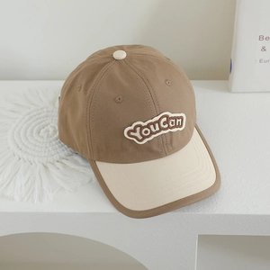 Détail de la casquette de baseball bicolore avec broderie You Can et texture en toile