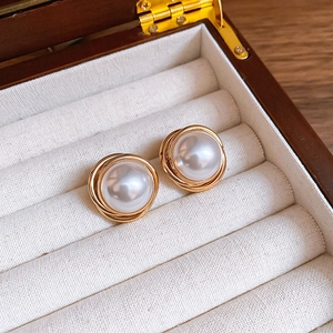 Close-up of vintage golden spiral stud earrings with elegant white faux pearls