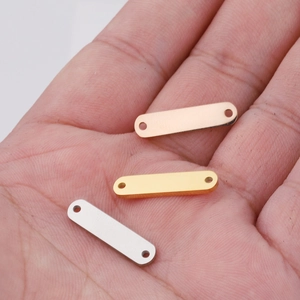 Macro shot of rectangular metal connector tags in rose gold, gold and silver on a palm