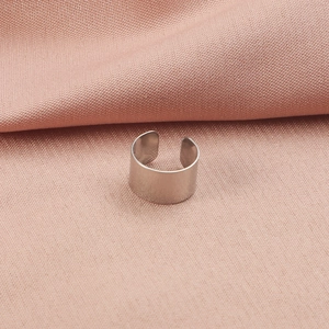 Polished silver stainless steel C-shaped ear cuff on soft pink fabric background
