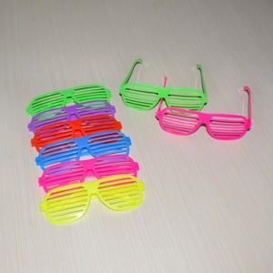 Multiple colorful shutter shade glasses for parties laid on a light wood background