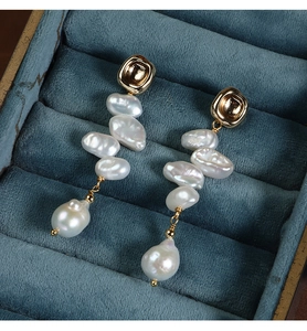 Macro shot of long baroque pearl earrings with gold plating on velvet jewelry box