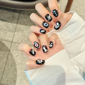 Handmade Halloween press-on nails featuring black base with white skull and bone patterns