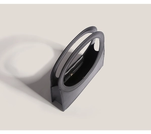 High-angle view of a dark grey minimalist handbag with unique integrated circular handle