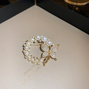 Vue détaillée de la broche papillon fleur dorée avec perles et pompons mobiles