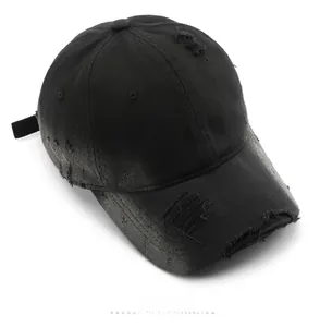 Top view of a black washed cotton baseball cap featuring vintage distressed rip details