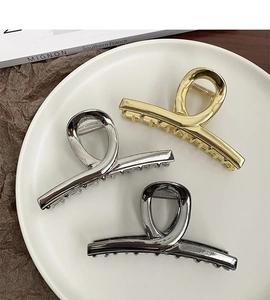 Detailed view of large metal shark hair clips in gold, silver, and gun black finishes