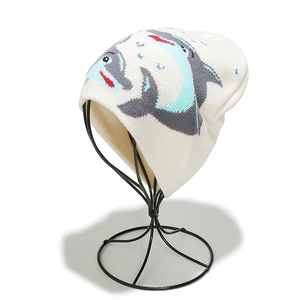 Détail du bonnet en tricot blanc avec un joli motif de dauphin en dessin animé gris et bleu