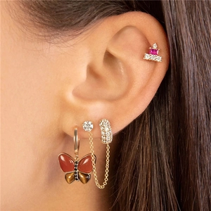 Macro shot of silver tassel chain earrings with crystal studs and a red butterfly charm