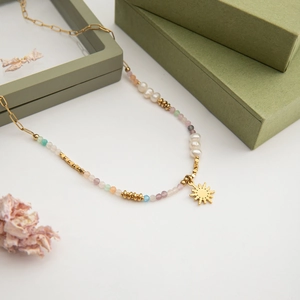 Detail of beaded necklace with freshwater pearls, colorful beads and sun pendant