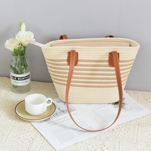 Detail of the woven tote bag showing its zipper closure, leather handles and striped texture