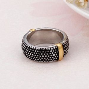 Macro detail of wide stainless steel ring featuring golden stripes and dotted texture