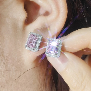 Close-up of pink emerald-cut earrings with shimmering crystal halo on ear