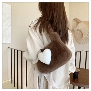 Brown plush shoulder bag with white heart detail worn by a model in casual setting