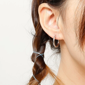 Close-up of minimalist silver stainless steel hoop earring worn by a model