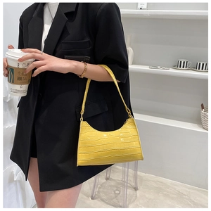 Close-up of bright yellow faux leather baguette bag with premium crocodile pattern texture