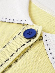 Macro shot of knit sweater collar with wave stitching and navy blue button detail