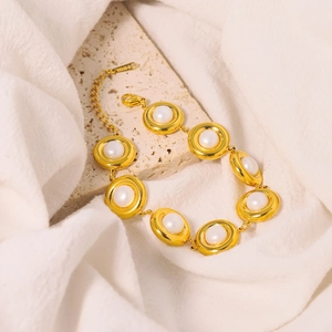 Elegant gold stainless steel bracelet with white pearls on a natural stone base