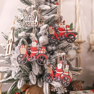 Wooden Christmas ornaments with Santa and reindeer on bicycles hanging on snowy tree