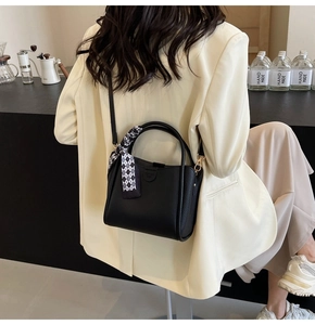 Close-up of black lychee grain bucket bag with decorative scarf and shoulder strap