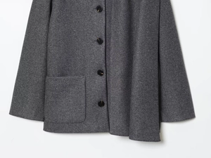 Detail view of dark grey wool coat with round buttons and large side pocket stitching