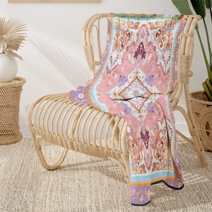 Bohemian floral flannel throw blanket with ethnic patterns draped on a rattan chair