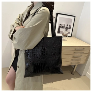 Detail of large black crocodile pattern tote bag shown with an elegant office trench coat