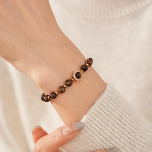 Détail macro du bracelet en perles d'oeil de tigre avec breloque sertie de cristaux