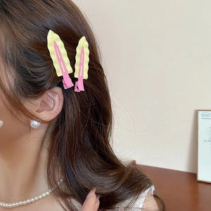 Detail of yellow and pink wavy metal hair clips worn on side hair for a stylish look