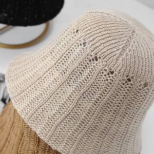 Close-up of beige hollow knit bucket hat with breathable weave texture and bow detail