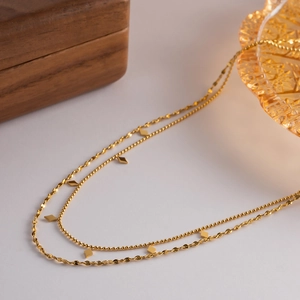 Close-up of golden double-layer necklace with beaded chains and diamond-shaped pendants
