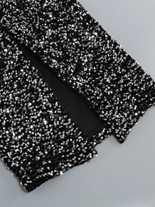 Détails macro d'une robe noire à manches longues avec paillettes argentées et fente
