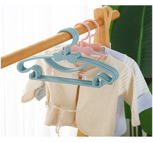Close-up of pink and blue plastic bow hangers for kids on a wooden clothing rail