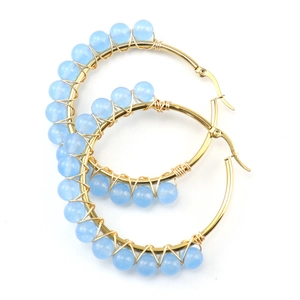 Detail of handmade wire-wrapped gold hoop earrings featuring light blue natural stone beads