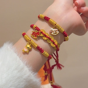 Close-up of woven red cord bracelets with gold horse and elephant charms on wrist