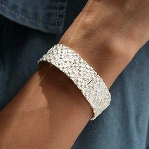 Détail d'un bracelet large en métal argenté avec motif de carrés en relief