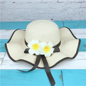 Detail of wide brim straw sun hat with white frangipani flowers and brown ribbon