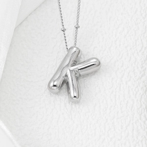 Macro shot of silver letter K pendant with high-polished mirror finish and fine bead chain