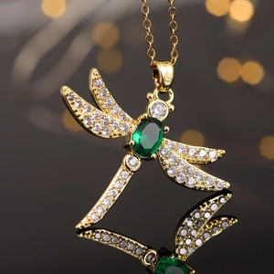 Macro detail of golden dragonfly pendant with green oval stone and white zircon stones