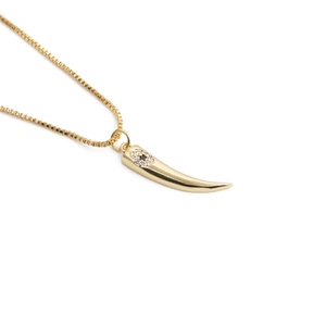 Golden wolf tooth pendant necklace with evil eye crystal inlay on white background