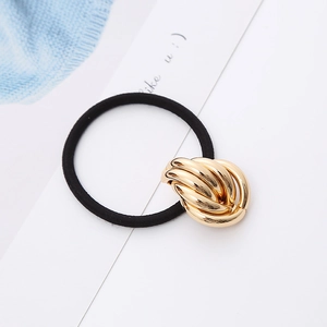 Detailed shot of black elastic hair tie with a decorative golden metal knot ornament