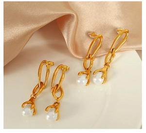 Detail of 18K gold chain link earrings with white pearl drop on silk background